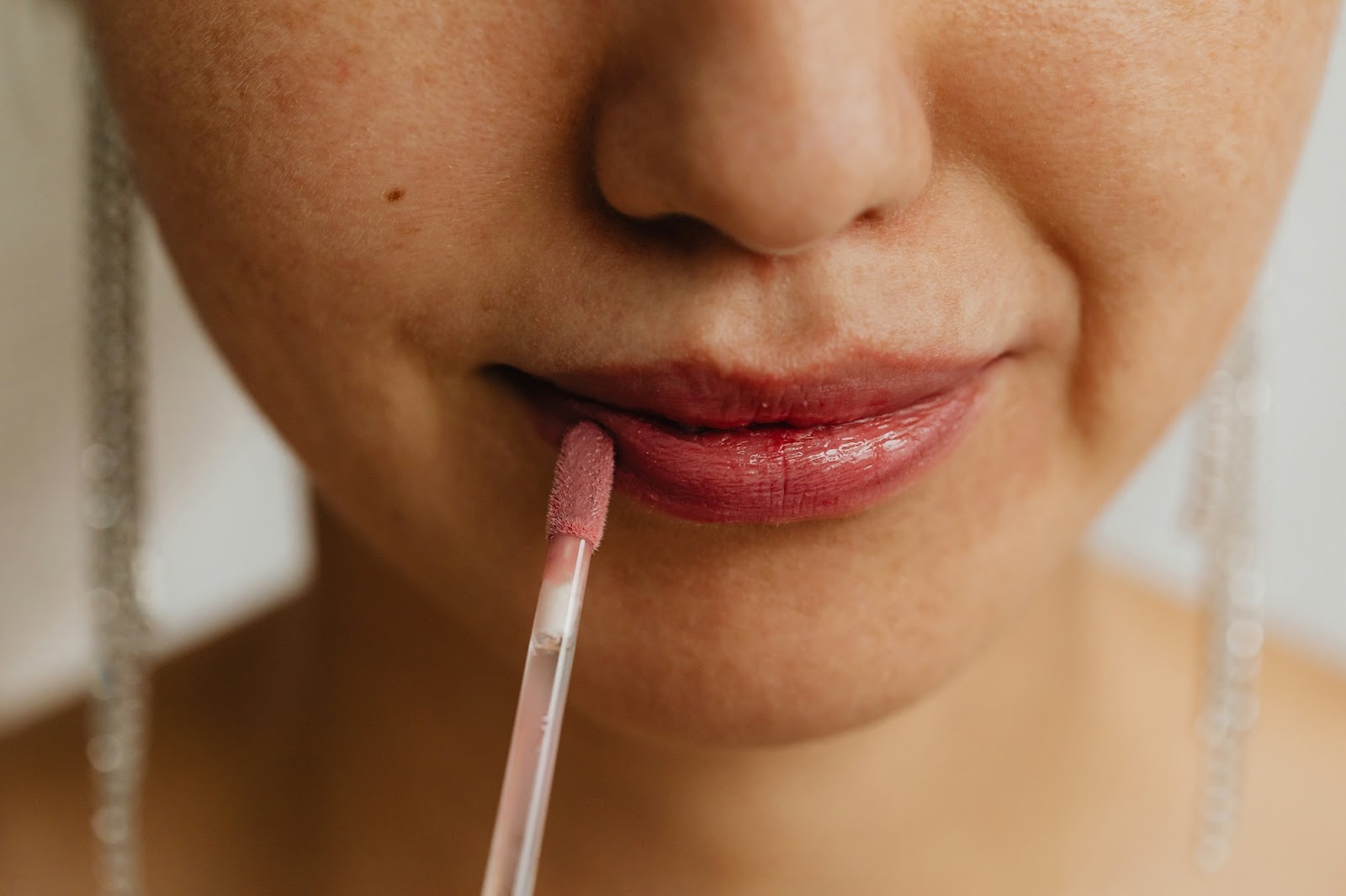 Female patient putting on lip gloss after going to Vive Aesthetics & Wellness for Juvederm lip filler near Moorestown, NJ.